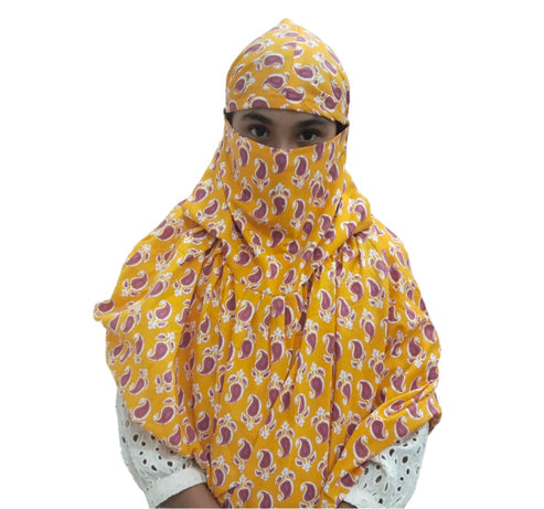 A girl wearing a yellow and purple paisley-patterned hijab that covers their head, neck, and most of their face, with only their eyes visible.